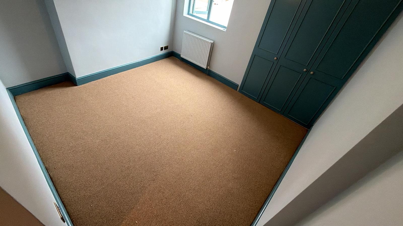 Beige wool bedroom carpet with deep teal fitted wardrobes